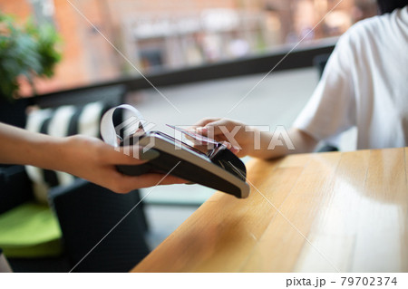 Asian Woman pay with credit card contactless payment terminal cashier in outdoor cafe Asian Woman pay with credit card contactless payment terminal cashier in outdoor cafe 79702374