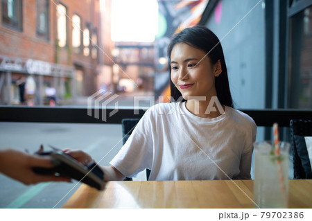 Asian Woman pay with credit card contactless payment terminal cashier in outdoor cafe Asian Woman pay with credit card contactless payment terminal cashier in outdoor cafe 79702386