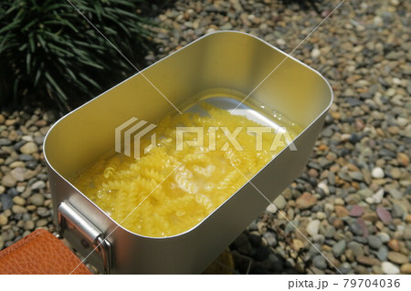 Fusilli pasta being boiled in a mess tin under the sun. Fusilli pasta being boiled in a mess tin under the sun. 79704036