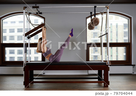 Modern equipment Cadilac reformer for Pilates in the gym, Concept of health and rehabilitation, instructor performs exercises on the reformer to correct the musculoskeletal system. 79704044