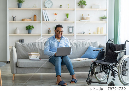 Handicapped black freelancer in wheelchair doing work project, speaking with boss, having online conference at home Handicapped black freelancer in wheelchair doing work project, speaking with boss, having online conference at home 79704720