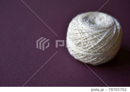 A white spool of thick threads on a purple background A white spool of thick threads on a purple background 79705702