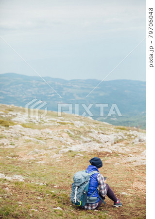 a woman looks at a smartphone on top of a mountain on a hiking trip a woman looks at a smartphone on top of a mountain on a hiking trip 79706048