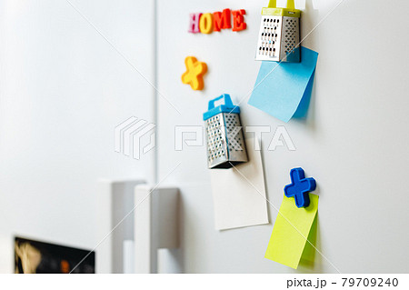 Sheets of paper and magnets on fridge door in kitchen Sheets of paper and magnets on fridge door in kitchen 79709240