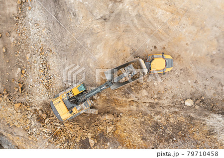 Heavy industrial excavator digs the ground and transfers it to the truck. Heavy industrial excavator digs the ground and transfers it to the truck. 79710458