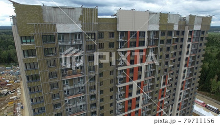A huge apartment building with a forest behind 79711156