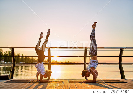 Couple doing practicing yoga together on nature outdoors . Morning exercises at the sunrise. Couple doing practicing yoga together on nature outdoors . Morning exercises at the sunrise. 79712104