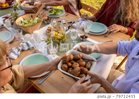 People Passing Tray of Baked Potatoes 79712435