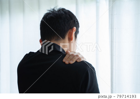 肩に手を置き窓辺に立つ男性の後ろ姿 肩に手を置き窓辺に立つ男性の後ろ姿 79714193