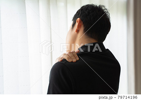 肩に手を置き窓辺に立つ男性の後ろ姿 79714196