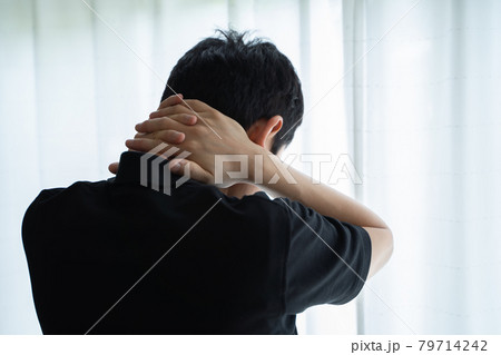 首に両手を置き窓辺に立つ男性の後ろ姿 首に両手を置き窓辺に立つ男性の後ろ姿 79714242