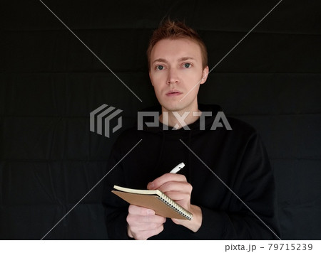 ボールペンでメモをとっている外国人男性　黒バック 79715239