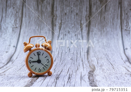 Orange old retro style alarm clock on wooden background Orange old retro style alarm clock on wooden background 79715351