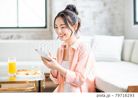 リビングで朝食を食べながらスマホを見る若い女性 リビングで朝食を食べながらスマホを見る若い女性 79716293