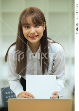 Portrait of attractive female employee smile while preparing financial papers Portrait of attractive female employee smile while preparing financial papers 79717855