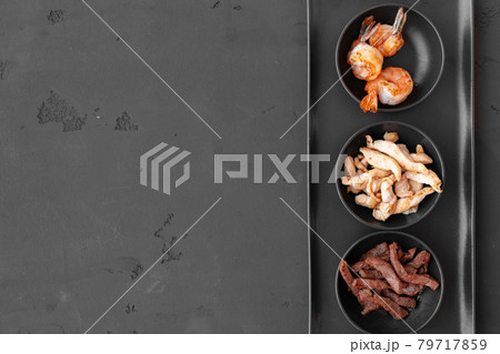 Three bowls with cooked beef, chicken slices and prawns on black background Three bowls with cooked beef, chicken slices and prawns on black background 79717859