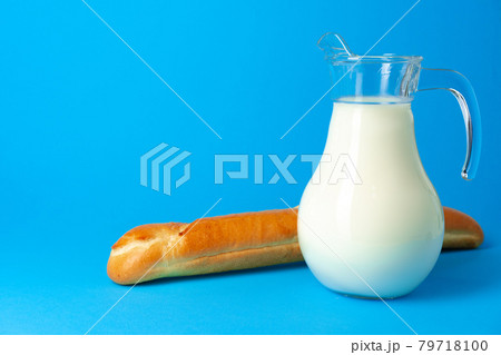 Fresh baguette bread and pitcher with fresh milk on blue background 79718100