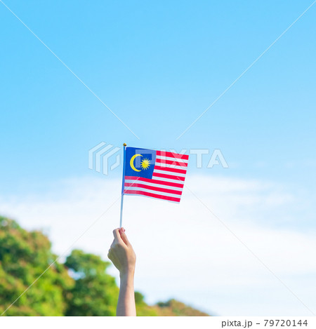 hand holding Malaysia flag on blue sky background. September Malaysia national day and August Independence day 79720144