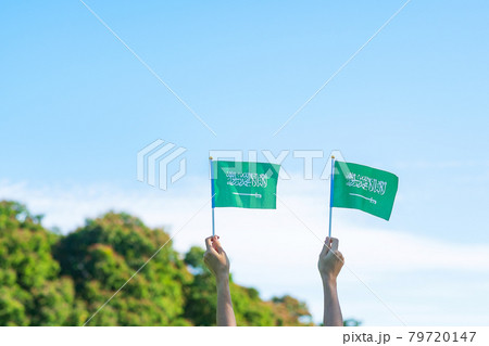 hand holding Saudi Arabia flag on blue sky background. September Saudi Arabia national day and Happy celebration concepts 79720147