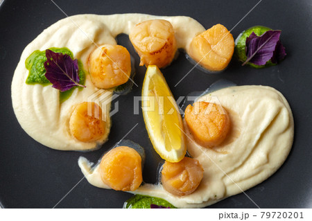 Scallops in creamy sauce on black plate 79720201
