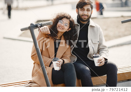Interracial young couple with scooters in the city background 79721412