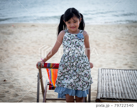 Portrait of Asian seven years girl standing on a beach chair on the beach on a summer day.	 79722540