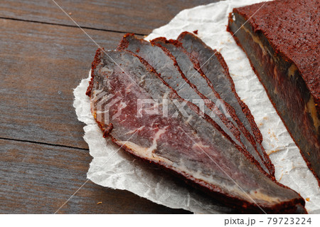 Sliced basturma meat on brow wooden background Sliced basturma meat on brow wooden background 79723224