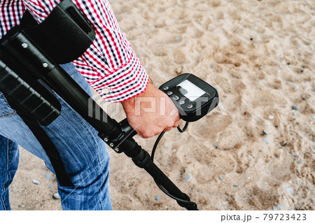 Male hand holding metal detector device above the ground Male hand holding metal detector device above the ground 79723423