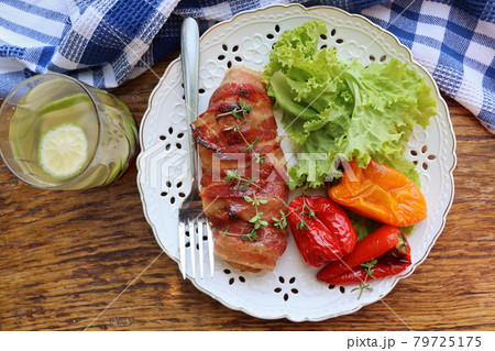 Dinner background. Grilled chicken breast wrapped in bacon served with salad on wooden rustic table . Top view . Dinner background. Grilled chicken breast wrapped in bacon served with salad on wooden rustic table . Top view . 79725175