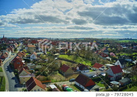 Aerial view of a village in Germany in bright sunshine with cloudy sky and many gardens and lawns 79728045