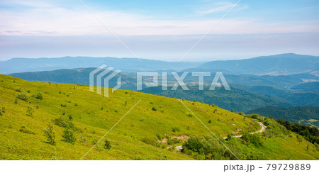 country road through the hill. mountain landscape in morning light. blue sky with clouds on a horizon above the distant ridge. rural valley between the rolling hills in the distance 79729889