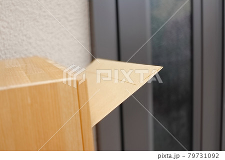 玄関横の木製のポストに投函された大型の茶封筒 79731092