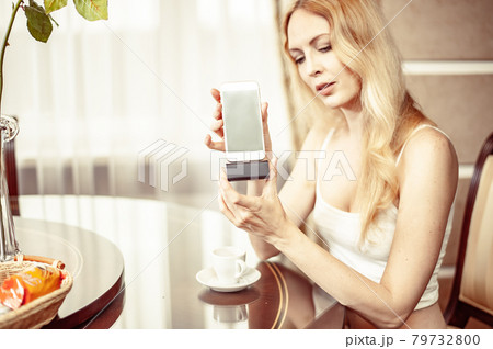 Beautiful young adult blond woman Holds a mobile phone 79732800