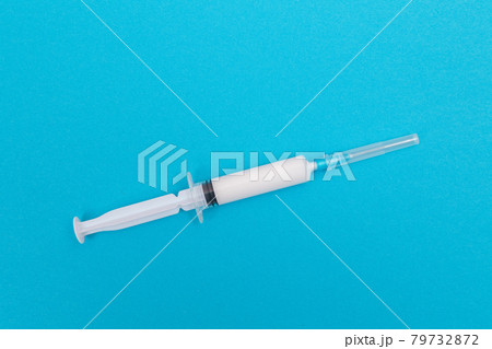 A Syringe with White Liquid Inside on Blue Table A Syringe with White Liquid Inside on Blue Table 79732872