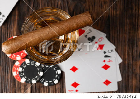 Playing poker with whiskey and cigars on table 79735432