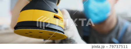 Master builder in protective mask is holding disc sander Master builder in protective mask is holding disc sander 79737511