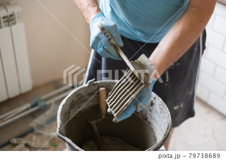 Man applying adhesive on tiles during flat renovation. Man applying adhesive on tiles during flat renovation. 79738689