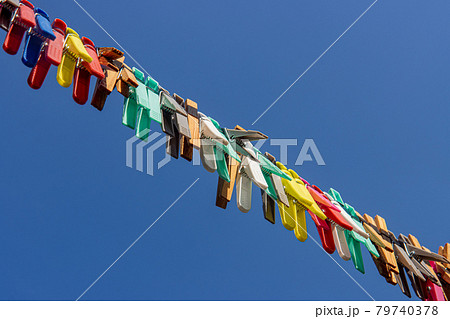 A colored clothes pegs hanging on a rope in nature. A group of clothespin in line against the blue. A colored clothes pegs hanging on a rope in nature. A group of clothespin in line against the blue. 79740378