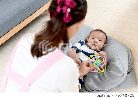 女性保育士が赤ちゃんをおもちゃであやすイメージ 79740729