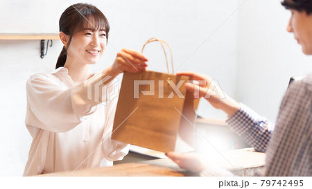 紙袋に入れた商品をお客に手渡す女性スタッフ 紙袋に入れた商品をお客に手渡す女性スタッフ 79742495