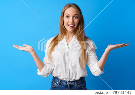 Surprised young blonde woman throwing up her hands against beige background Surprised young blonde woman throwing up her hands against beige background 79743445
