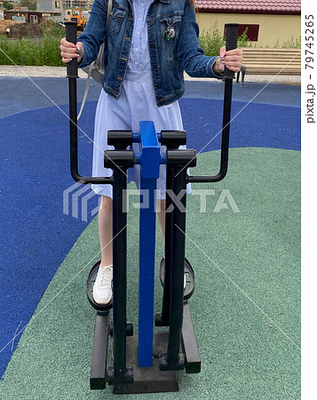 A woman goes in for sports on a new modern blue fitness leg trainer for walking and running on an outdoor workout site 79745265
