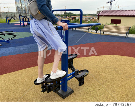A woman goes in for sports on a new modern blue fitness leg trainer for walking and running on an outdoor workout site 79745267