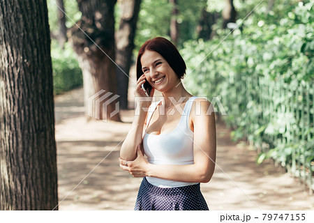 Girl laughs talking on a smartphone and walking in the park 79747155