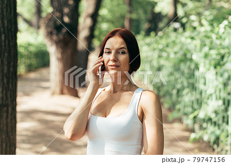 Girl talking thoughtfully on a smartphone while walking in the park 79747156