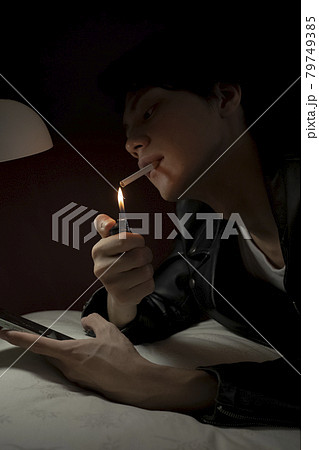 ベッドでタバコを吸う男性の写真素材