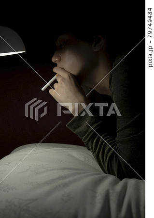 ベッドでタバコを吸う男性 79749484