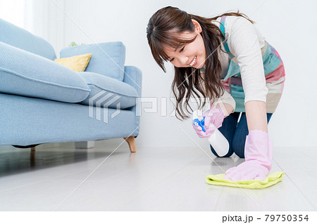 リビングの床に洗剤をスプレーしながら拭き掃除をする女性 79750354