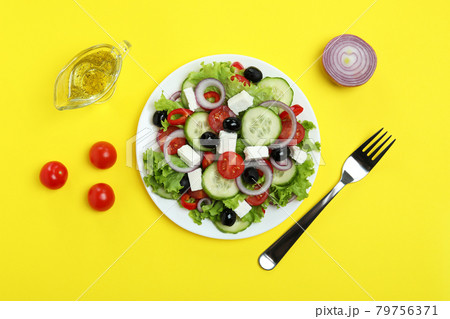 Concept of delicious food with Greek salad on yellow background 79756371