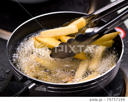 Close up of Frying french fries in the fryer in hot oil on the electric stove in the kitchen. Making homemade french fries. Close up of Frying french fries in the fryer in hot oil on the electric stove in the kitchen. Making homemade french fries. 79757199